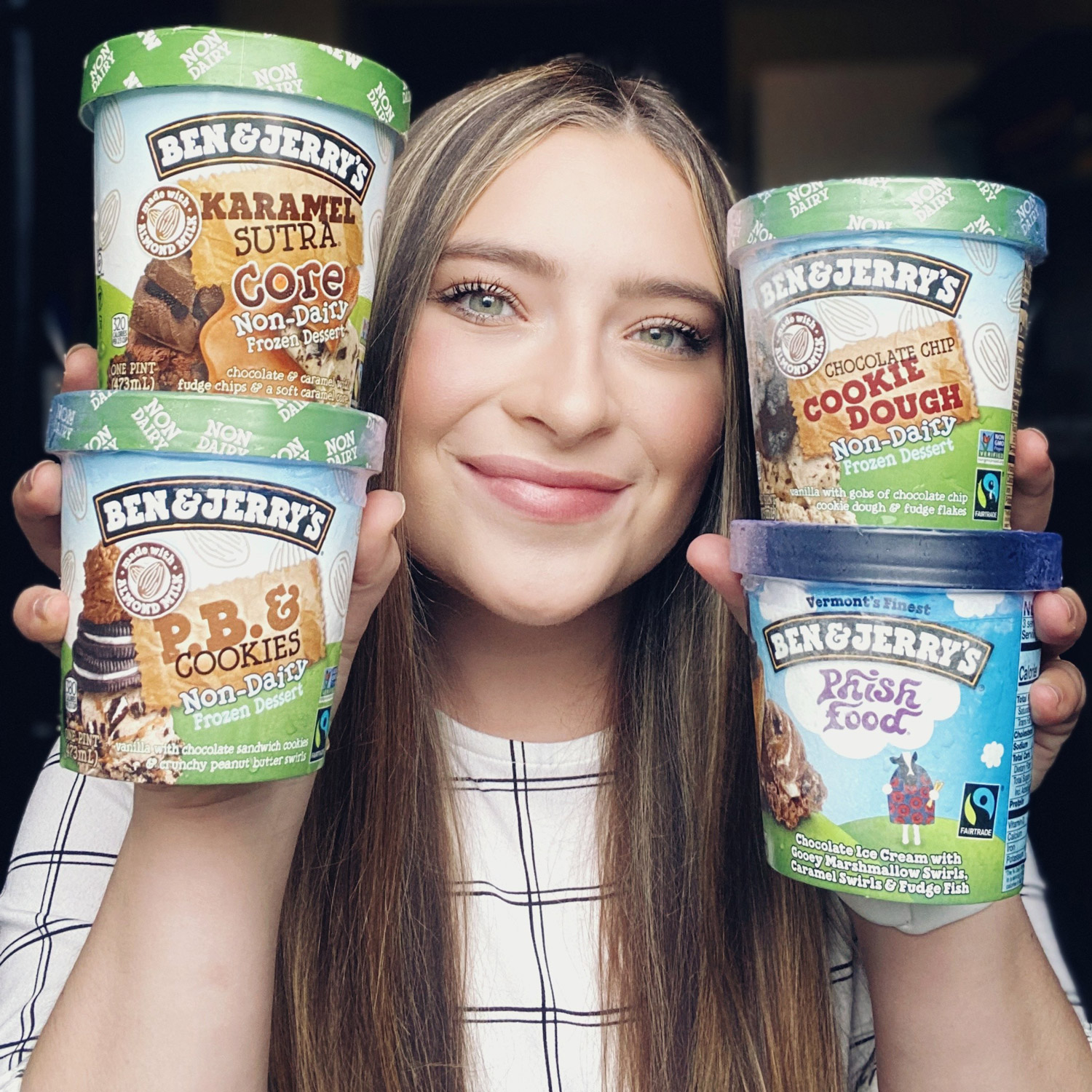 A female student holds pints of ice cream up next to her face