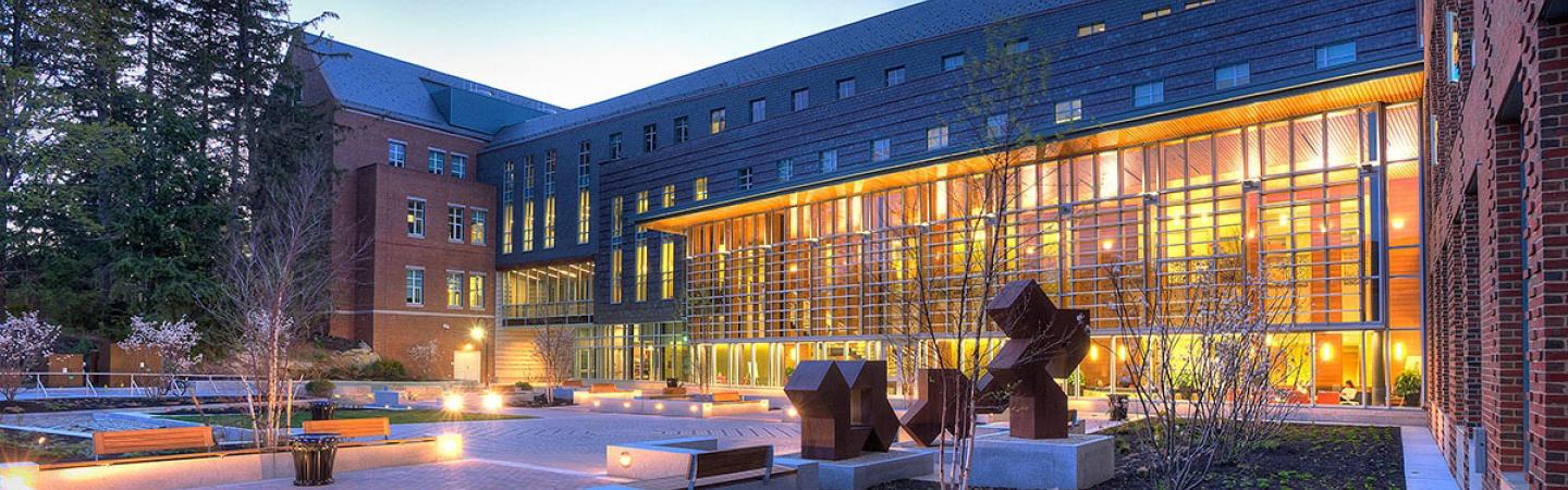 Paul College courtyard in the evening with interior lights aglow