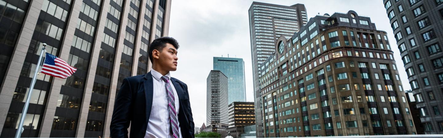 Ashim Gurung '22 stands outside along a Boston skyline