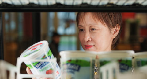 Professor of Marketing Shuili Du examines a container of Stonyfield Farm yogurt, highlighting her research on corporate social responsibility initiatives of yogurt brands.
