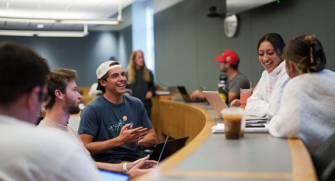 UNH business school students gather in a classroom to chat before class begins.