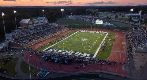 An aerial shot of the UNH football stadium, with the team playing a game on the field and full stands.