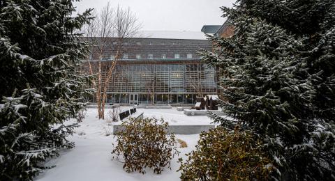 Snow covered trees flank the foreground, while the paul college building can be seen in the background behind the snow covered courtyard