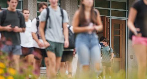to college students walking in from of the UNH Paul College of Business and Economics