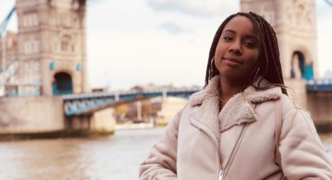 A female student stands in front of london bridge.