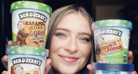 A female student holds pints of ice cream up next to her face