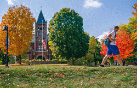student walking in front of Thompson Hall on a fall day