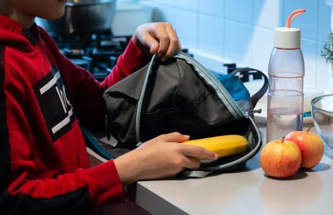 A child unpacking healthy food from a backpack