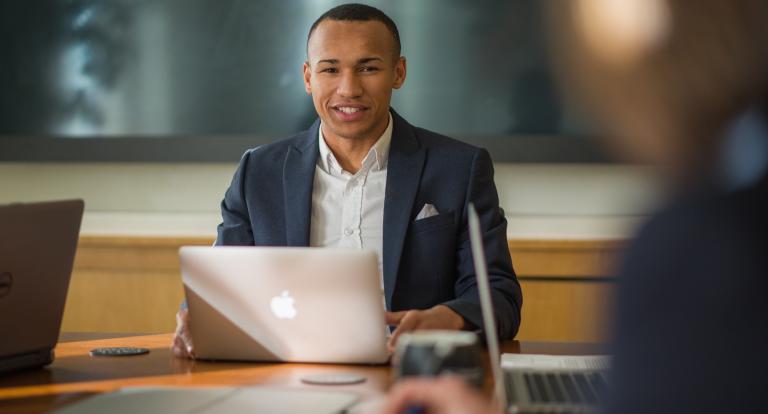 UNH Full-time MBA student Dante Lamb works at conference table with laptop