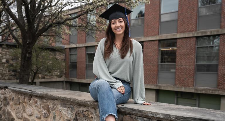 Emily smiles at the camera while wearing a graduation cap
