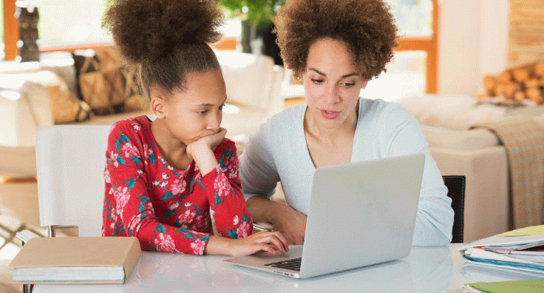 Black mother helping daughter with homework on laptop GETTY