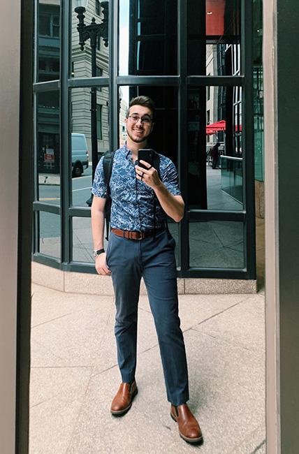 A male student poses in a reflective building in Boston.