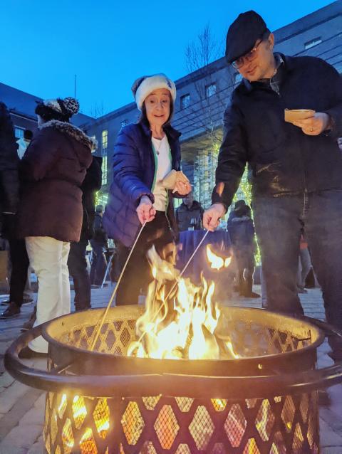 Economics faculty members toasting marshmallows for smores