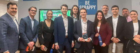 Professionally dressed students pose with Professor James McIlroy after sales competition