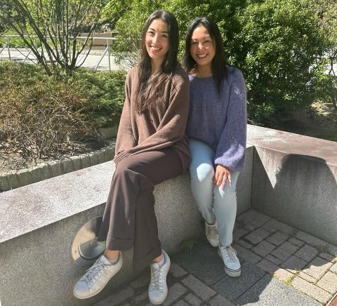 Leni and Michelle Lemos sit outside the Peter. T Paul College of Business and Economics