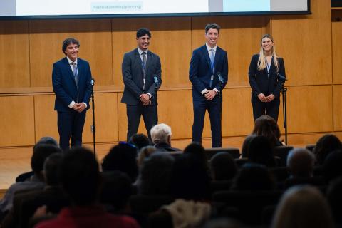 Four people participating in UNH's Holloway Competition stand on stage during their presentation.