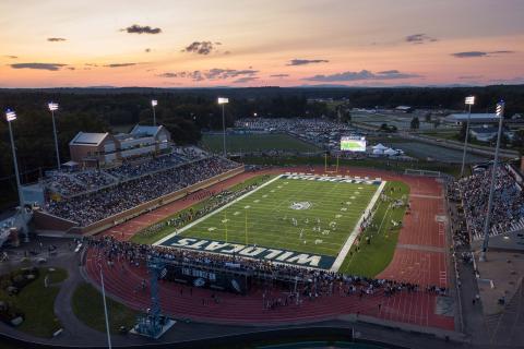 An aerial shot of the UNH football stadium, with the team playing a game on the field and full stands.