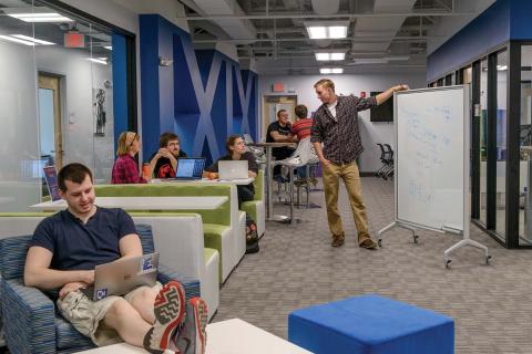 Students gather in the UNH Entrepreneurship Center's coworking space, some at tables and others at whiteboards and soft seating.