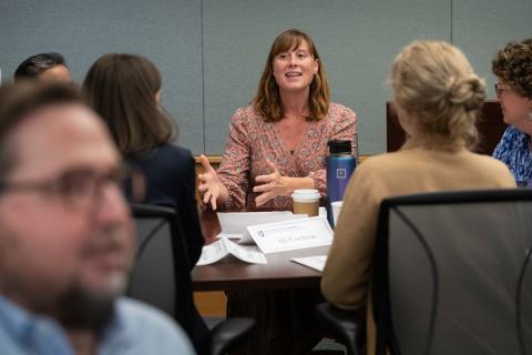 Students within UNH Paul College's Executive Education program chat at a table together in a classroom.