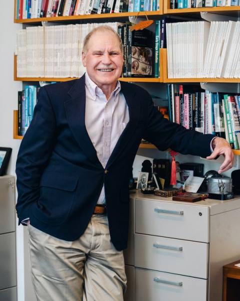 Jeffrey Sohl; male, professioanlly dressed leans against a filing cabinet, and poses with a smile