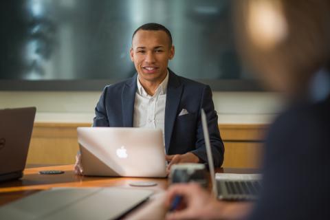 UNH Full-time MBA student Dante Lamb works at conference table with laptop