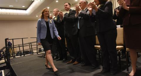 Mayor Craig walking across stage while people stand and clap