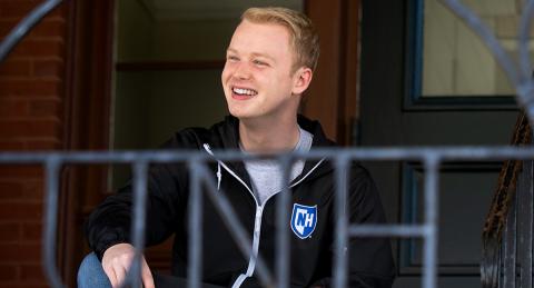 Michael Dambach smiles off camera behind a wire UNH fence design.