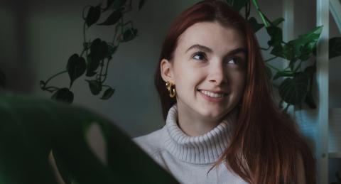 Kenzie Gagne smiles among some of her house plants