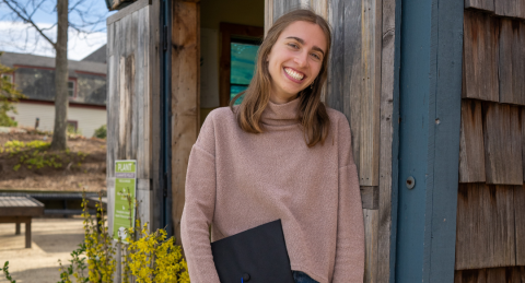Zara Cheney leans against a shed, smiling