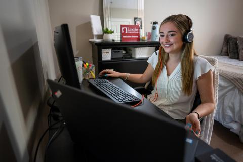 Claudia Fox sits at a desk looking at a computer screen in her Durham apartment.