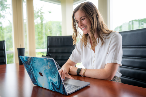 A female student sits at a table with her laptop